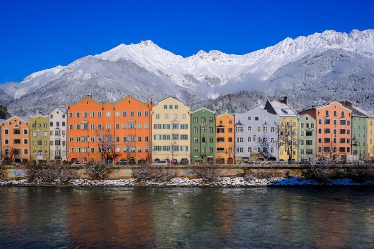 Panorama zabudowań miasta Innsbruck, Austria. Za kolorowymi kamienicami widoczne ośnieżone szczyty gór.